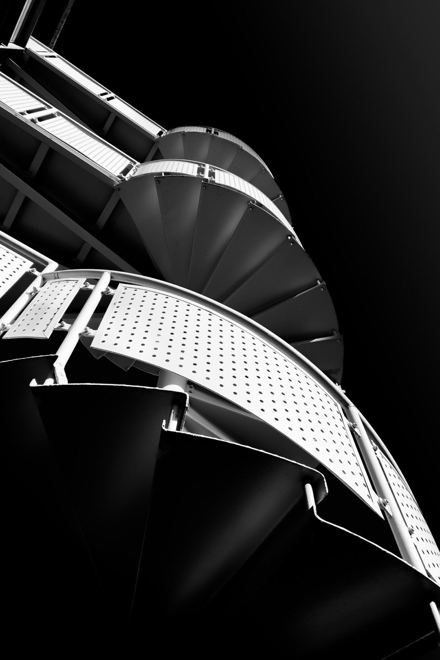 A spiral staircase seen from below, its steps curving upward