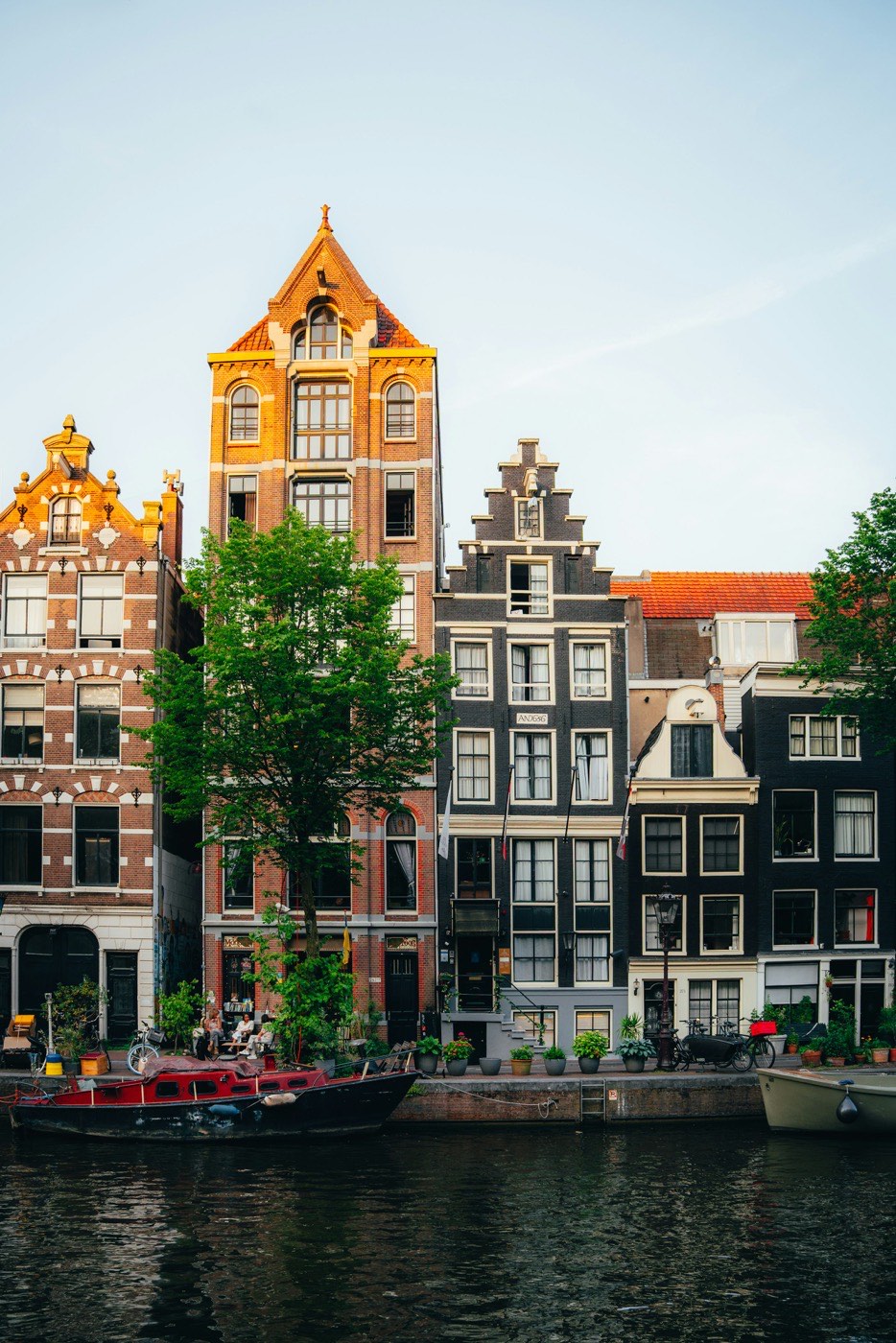 Row of Amsterdam canal houses with distinct, unequal façade heights and rooflines side by side